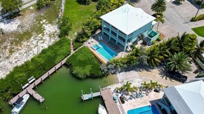 Un complexe hôtelier doté d’une piscine, d’un quai avec des bateaux et d’un bâtiment surmonté d’un toit bleu clair.