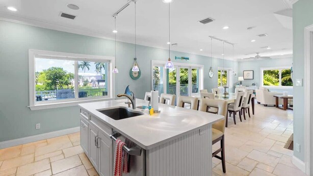 A spacious kitchen with a large island, a dining area with chairs, and a view of the outdoors.