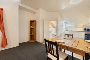 Un espace repas avec une table en bois, des chaises et une cuisine en arrière-plan.