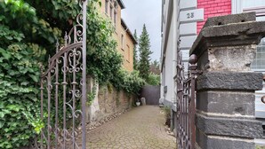 A narrow cobblestone alleyway with a wrought iron gate, a brick building, and a stone pillar. - Apartment 'Alte Stadtvilla' with Private Garden and Wi-Fi (Neuwied)