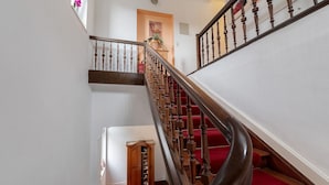 A staircase with wooden balusters and red carpeted steps leading to a landing. - Apartment 'Alte Stadtvilla' with Private Garden and Wi-Fi (Neuwied)