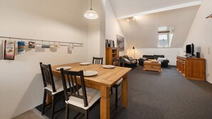 A dining area with a wooden table and chairs, a sofa, a TV, and a window. - Apartment 'Alte Stadtvilla' with Private Garden and Wi-Fi (Neuwied)