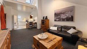 A spacious living area with a wooden coffee table, a leather sofa, and a cityscape painting on the wall. - Apartment 'Alte Stadtvilla' with Private Garden and Wi-Fi (Neuwied)