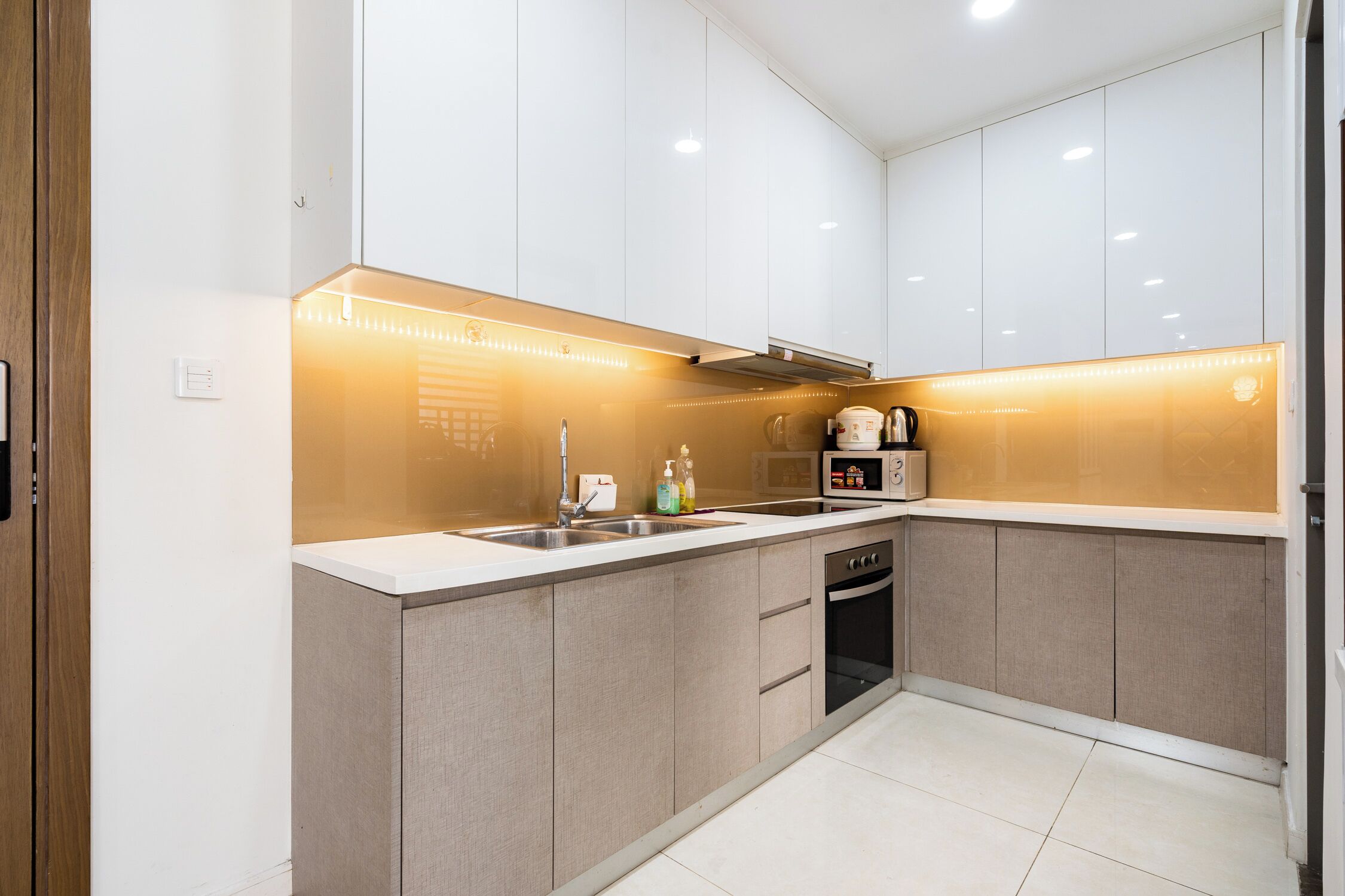 A modern kitchen with white cabinets, a stainless steel sink, and a built-in oven.