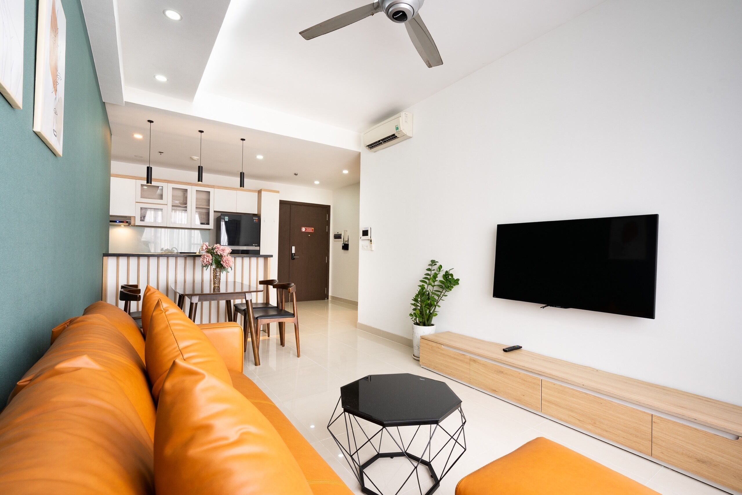 Una sala moderna con un sofá, una televisión y un comedor al fondo.
