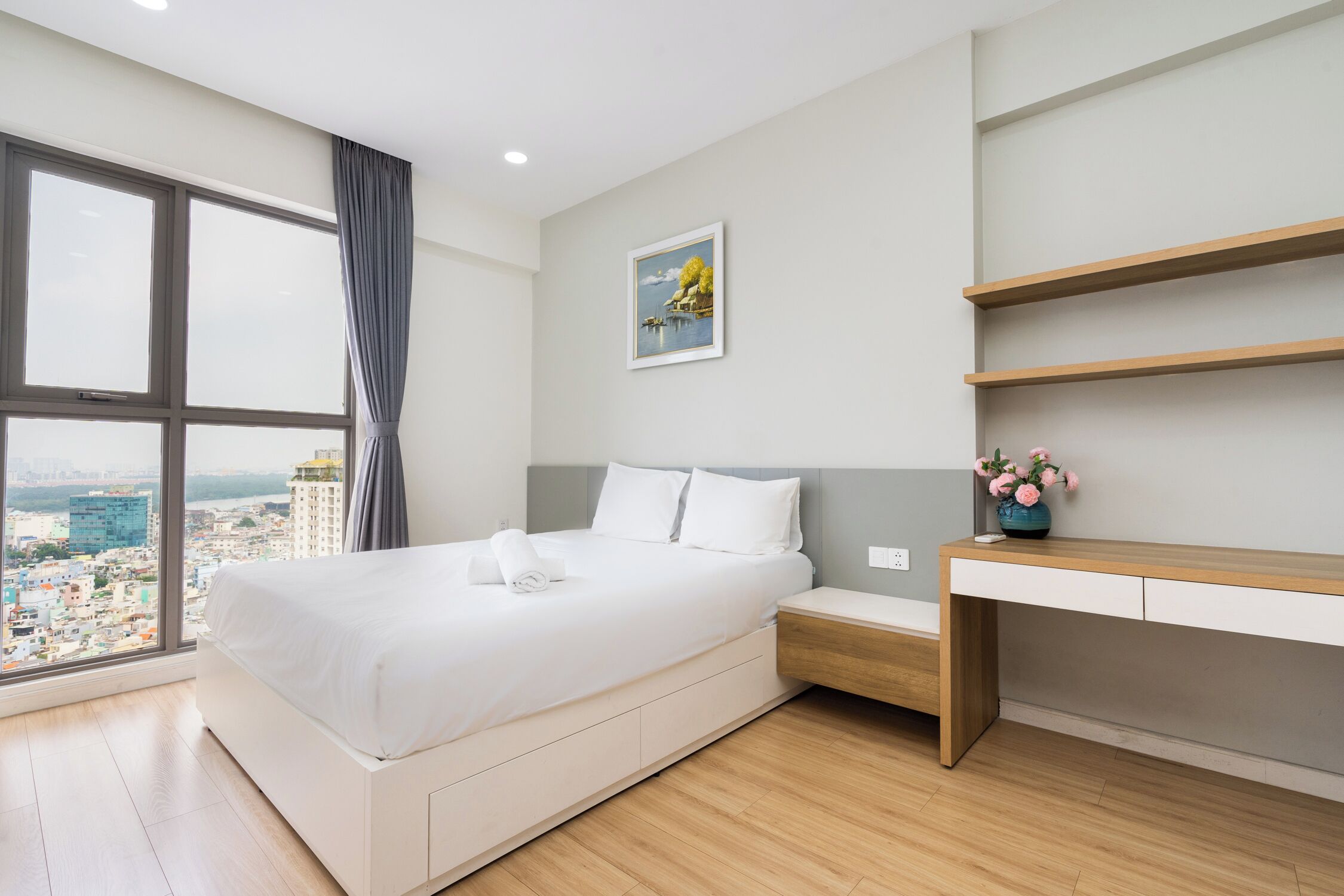 A modern hotel room with a large bed, a desk, and a city view.
