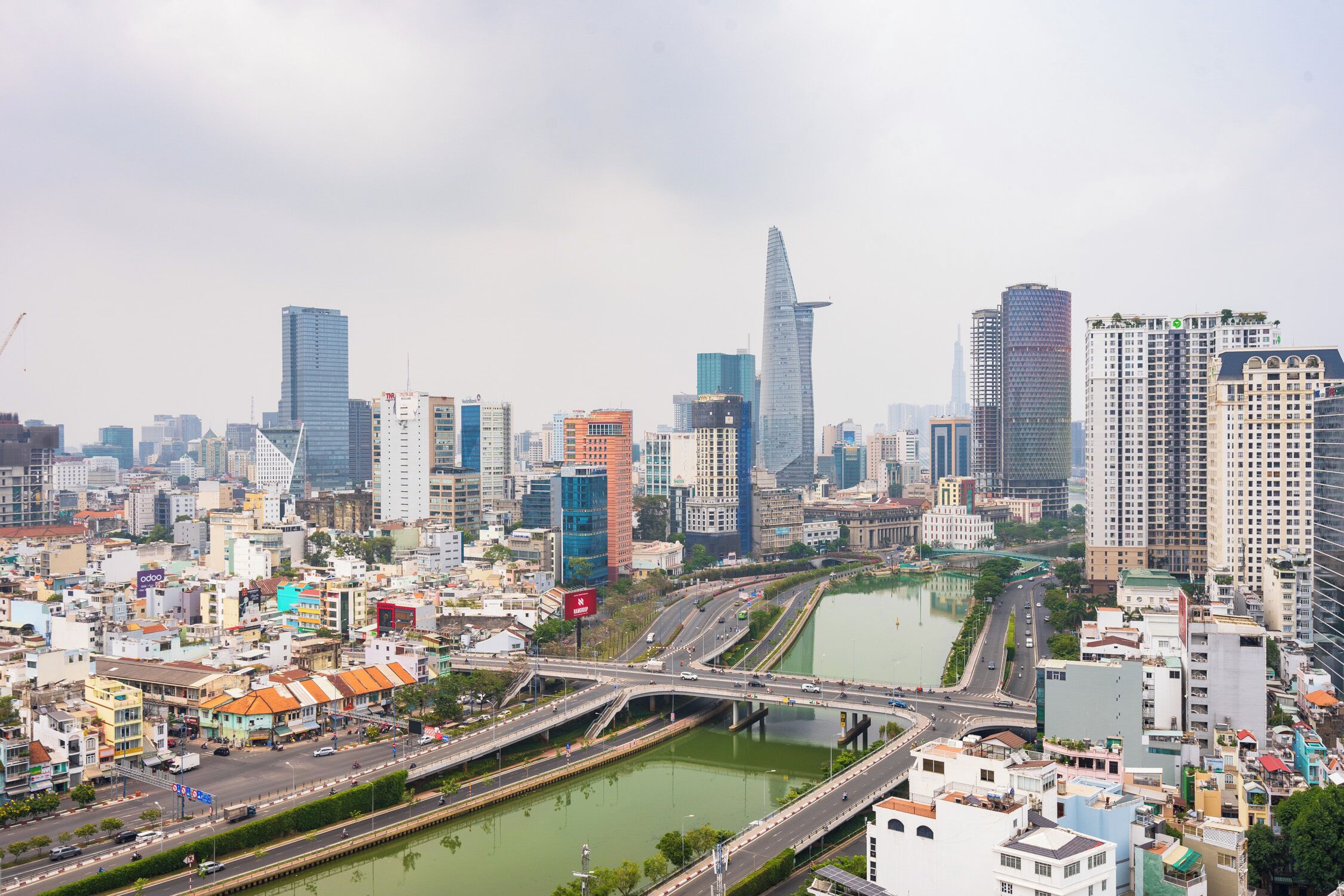 A cityscape with modern high-rise buildings, a river, and a bridge.