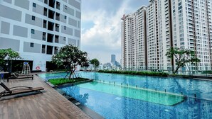 A modern apartment building with a rooftop swimming pool, surrounded by greenery and equipped with sun loungers. - KaLa RiverGate Apartment - Ben Thanh (Ho Chi Minh City)