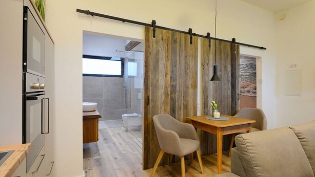 A modern kitchen with a sliding door leading to a bathroom. - Deichloft Modern Retreat (Wurster Nordseeküste)
