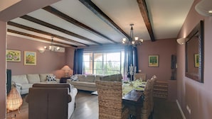 Un coin repas avec une table en bois, des chaises en osier et un lustre.