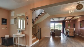 Un vaste espace de vie comprenant un escalier, une table à manger avec des chaises et un grand miroir.