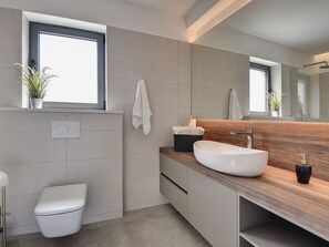 A modern bathroom with a large mirror, a wooden vanity, a white sink, and a toilet. - Apartment in Croatia by the Adriatic Coast (Medulin)