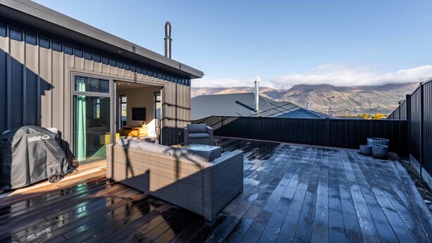 A rooftop patio with a wicker sofa, a grill, and a view of mountains. - Cosy Kirimoko Escape in Wanaka (Wānaka)