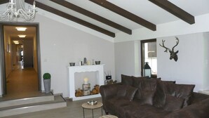 Una sala de estar con un sofá de cuero marrón, una chimenea, un candelabro y una cabeza de ciervo montada en la pared.