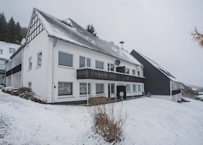 A two-story house with a balcony, satellite dishes, and a snow-covered landscape. - Ferienwohnung mit Terrasse bei Winterberg (Winterberg)