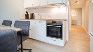 A compact kitchen with white cabinets, a built-in oven, and a wooden countertop.