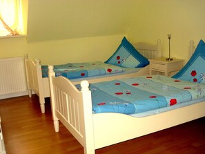 A bedroom with two single beds, each with a floral bedspread and matching pillows.