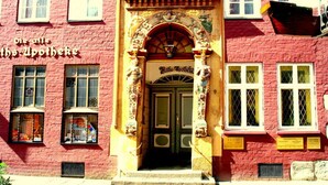 A red brick building with ornate architectural details, including a decorative archway and a sign reading "Die Apotheke". - Holiday Apartment Bella Rosa Luneburg (Reppenstedt)