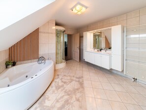 Ein modernes Badezimmer mit freistehender Badewanne, einer Duschkabine aus Glas und einem Waschtisch mit großem Spiegel.