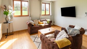Un salon avec un canapé marron, une table basse et un téléviseur fixé au mur.