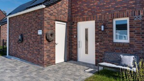 A brick building with a white door and a window marked with the number 23. - Holiday Home Meerperle (Butjadingen)