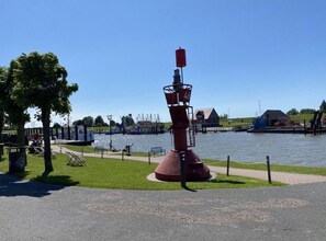 A lighthouse with a red top, situated by a body of water with a grassy area and a fence in the foreground. - Holiday Home Meerperle (Butjadingen)