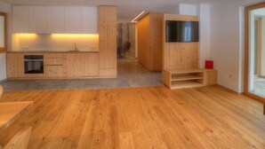 A modern kitchen with wooden cabinetry, a built-in oven, and a stainless steel range hood.