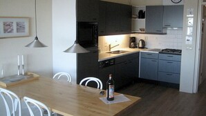 A compact kitchen with dark cabinets, a microwave, a coffee maker, and a clock on the wall. - Helmduin 5D Comfortable Holiday Residence (Egmond aan Zee)