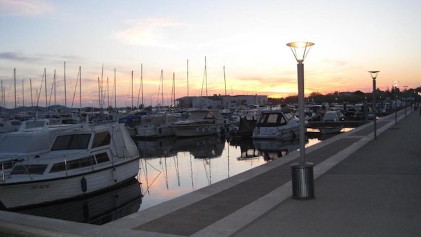 Un port de plaisance où des bateaux sont amarrés le long d’une promenade en bord de mer.