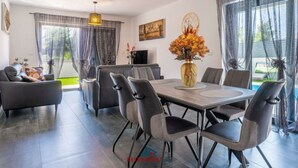 Un espace repas moderne avec une table rectangulaire, six chaises et un vase de fleurs.