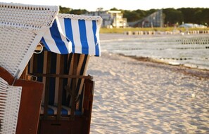 Una silla de playa con funda a rayas, una silla de mimbre y una estructura de madera.