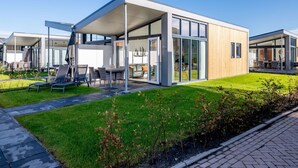 A modern house with a patio area, large windows, and a well-maintained lawn. - Modern Chalet With Beautiful Terrace, in Friesland (Akkrum)
