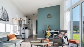 A modern living room with a grey sofa, a round coffee table, and a dining area with a table and chairs. - Modern Chalet With Beautiful Terrace, in Friesland (Akkrum)