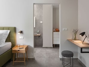 A modern hotel room with a green sofa, a wooden side table with a lamp, a small stool, and a desk with a lamp. - Villa Sent Comfortable Holiday Residence (Labin)