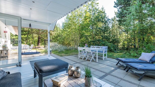 A covered outdoor seating area with a table, chairs, and a lounge chair. - 4 Star Holiday Home in Norre Nebel (Norre Nebel)