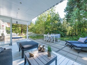 A covered outdoor seating area with a table, chairs, and a lounge chair. - 4 Star Holiday Home in Norre Nebel (Norre Nebel)