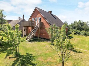 A two-story brick house with a wooden staircase leading to a deck.