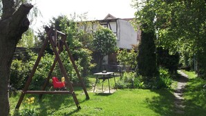 A grassy backyard with a swing set, a table, and a path leading to a house. - Comfort Apartment Comfortable Holiday Residence (Wernigerode)