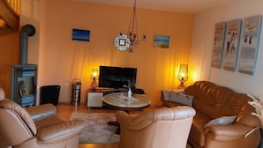 A cozy living room with a fireplace, leather sofas, a TV, and artwork on the walls. - Mari Comfortable Holiday Residence (Koserow)