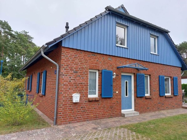 Une maison à deux étages, construite en briques, avec des volets bleus et un toit bleu.