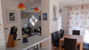Een moderne keuken met granieten aanrechtbladen, een eethoek met een houten tafel en zwarte stoelen, en hanglampen.