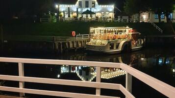 A boat docked at a pier with a lit-up building in the background.