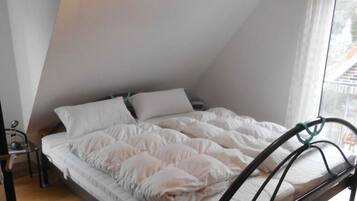 A bedroom with a bed in a sloped ceiling room, a bedside table, and a window.