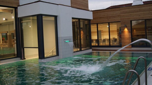 Een modern hotel met een zwembad, grote ramen en een houten gevel.