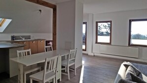 Una habitación amplia con comedor, sofá y ventanas grandes que ofrecen vistas al exterior.