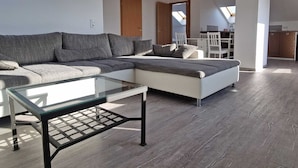 Una sala moderna con un sofá modular, una mesa de centro de vidrio y una cama.