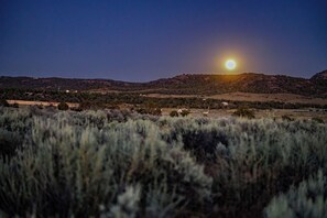 A landscape with a prominent hill and a bright moon in the sky.