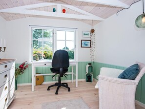 Quarto com escrivaninha, cadeira e vista para o verde lá fora.