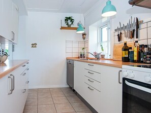 A kitchen with white cabinets, a wooden countertop, a dishwasher, and a stove. - 4 Person Holiday Home in Malling (Malling)