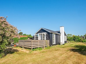 A single-story house with a dark exterior, a chimney, and a wooden deck. - 4 Person Holiday Home in Malling (Malling)